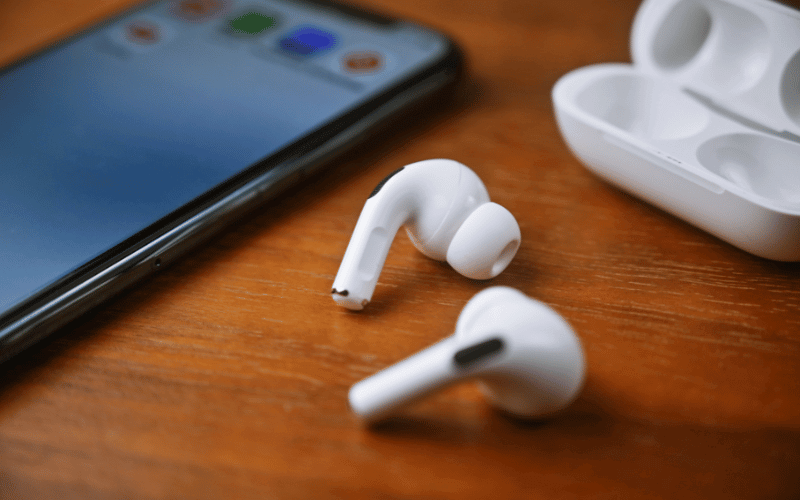 A imagem mostra um fone de ouvido bluetooth em cima da mesa com um celular ao lado