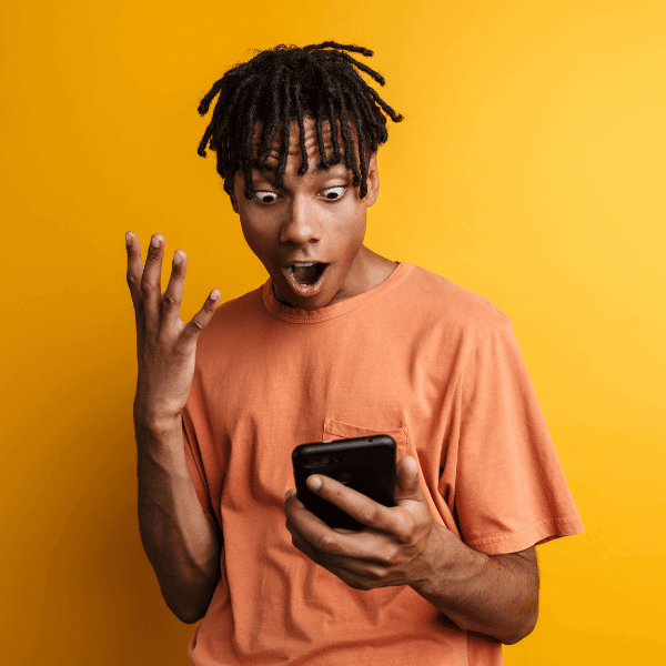 Imagem em fundo amarelo destacando um homem impressionado com um celular.